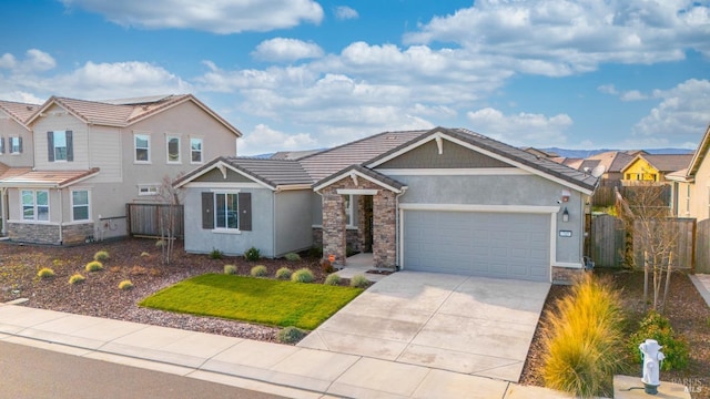 view of front facade featuring a garage, stone siding, concrete driveway, a tiled roof, and stucco siding