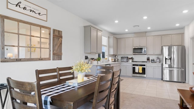 kitchen featuring light tile patterned floors, stainless steel appliances, a sink, light countertops, and gray cabinets