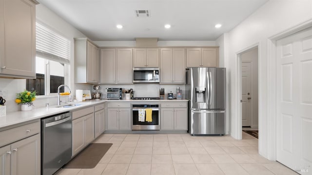 kitchen with stainless steel appliances, recessed lighting, light countertops, visible vents, and a sink