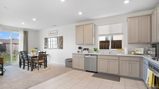 kitchen featuring appliances with stainless steel finishes, light countertops, a sink, and light colored carpet