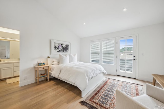 bedroom featuring lofted ceiling, light wood-style floors, ensuite bath, access to outside, and baseboards