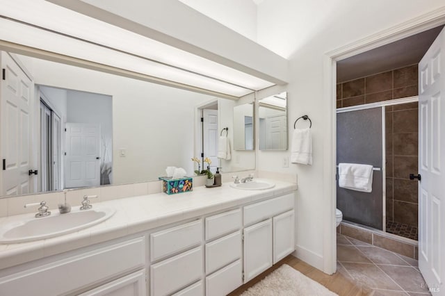 bathroom with double vanity, a stall shower, a sink, and toilet