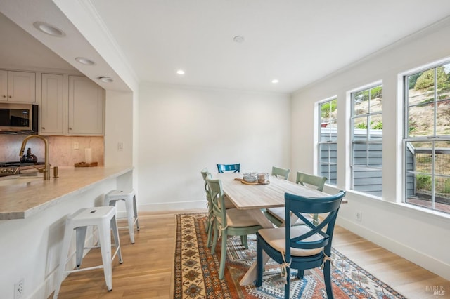 dining area with light wood finished floors, baseboards, crown molding, and recessed lighting