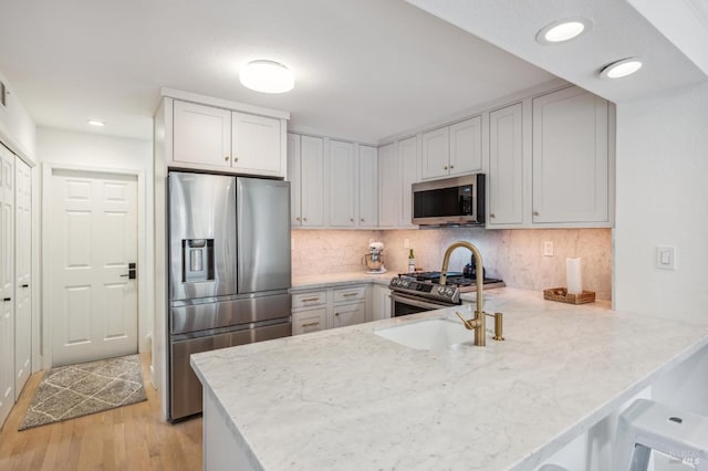 kitchen with a peninsula, white cabinetry, appliances with stainless steel finishes, and decorative backsplash