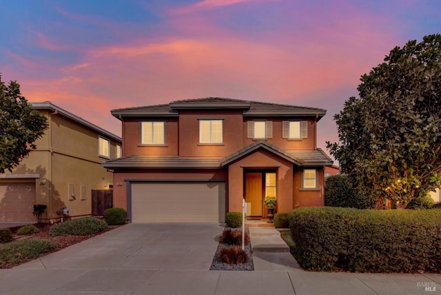 view of front of home featuring a garage, driveway, a tiled roof, and stucco siding