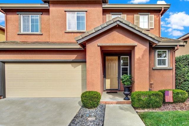 doorway to property with a garage, driveway, and stucco siding