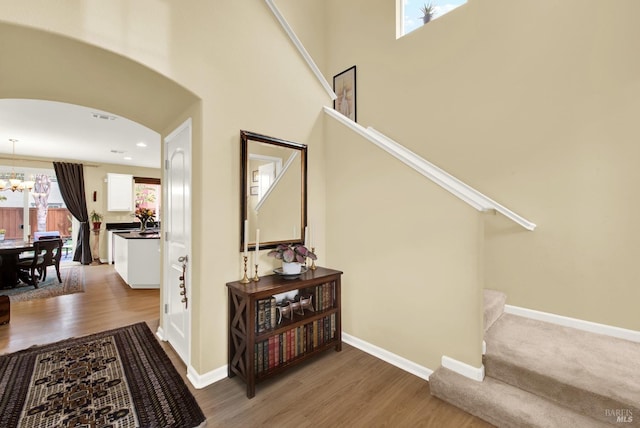 stairway featuring arched walkways, baseboards, and wood finished floors