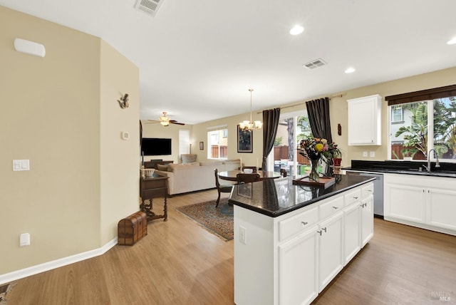 kitchen with white cabinetry, a sink, visible vents, and a center island