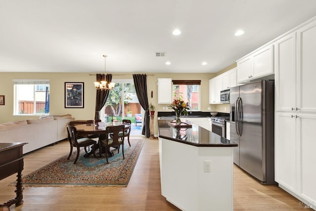 kitchen featuring visible vents, white cabinetry, hanging light fixtures, appliances with stainless steel finishes, and a center island