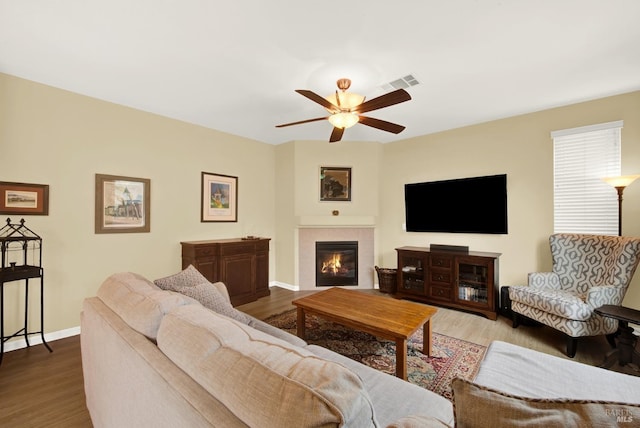 living room featuring baseboards, visible vents, ceiling fan, wood finished floors, and a fireplace