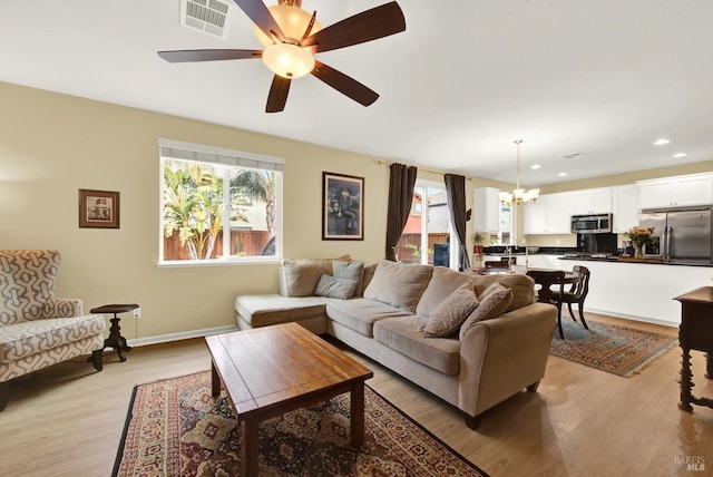 living room featuring recessed lighting, visible vents, light wood-style flooring, baseboards, and ceiling fan with notable chandelier