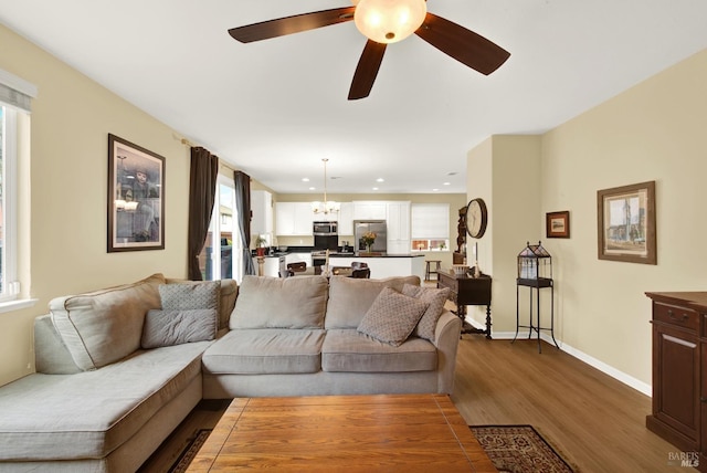 living room with ceiling fan with notable chandelier, recessed lighting, wood finished floors, and baseboards