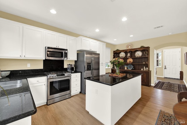 kitchen featuring visible vents, stainless steel appliances, a kitchen island, and white cabinetry