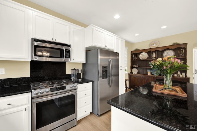 kitchen featuring stainless steel appliances, dark stone countertops, and white cabinetry