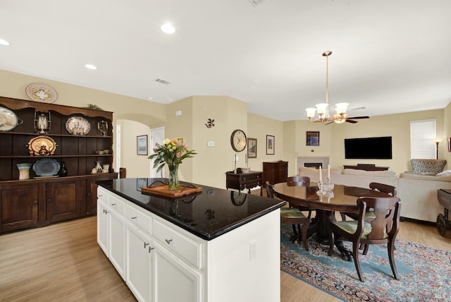 kitchen featuring open floor plan, light wood-type flooring, white cabinets, and a center island