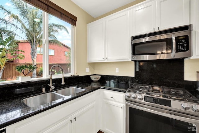 kitchen with dark stone counters, appliances with stainless steel finishes, and white cabinetry