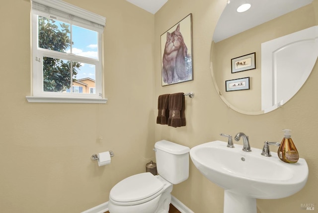 half bathroom featuring toilet, baseboards, and a sink