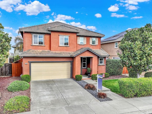 traditional-style house with an attached garage, fence, concrete driveway, a tiled roof, and stucco siding