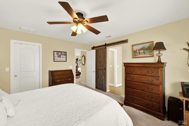 bedroom featuring a ceiling fan, visible vents, and a barn door