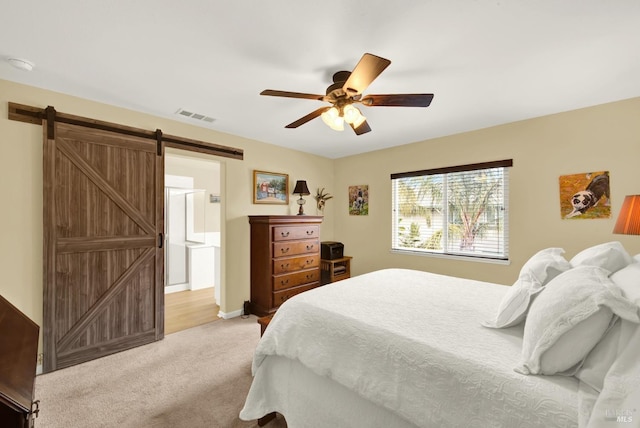 bedroom featuring a barn door, visible vents, connected bathroom, a ceiling fan, and light colored carpet