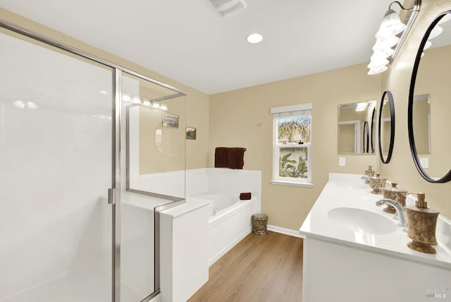 full bath with a garden tub, wood finished floors, a sink, and a stall shower