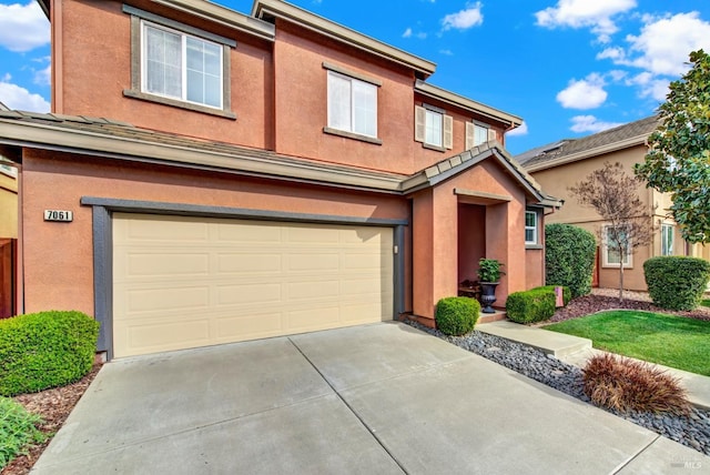 traditional home with concrete driveway, an attached garage, and stucco siding