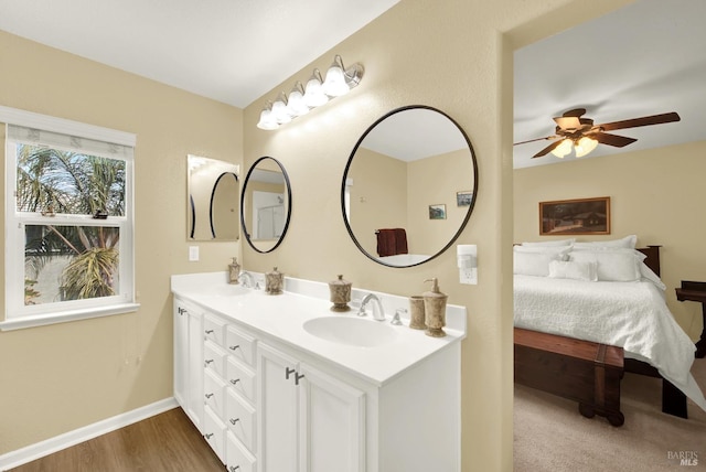 bathroom with double vanity, a sink, baseboards, and ensuite bathroom