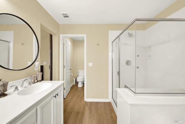 bathroom featuring a stall shower, visible vents, toilet, wood finished floors, and vanity