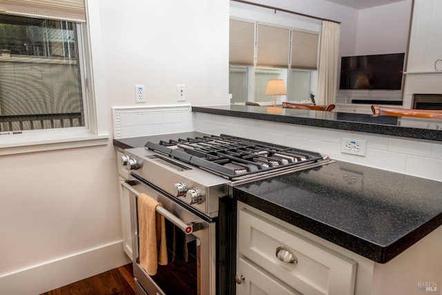 kitchen with baseboards, high end stove, dark wood-style floors, and white cabinetry