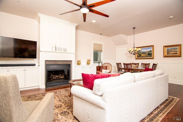 living room featuring a fireplace with flush hearth, dark wood-type flooring, ceiling fan with notable chandelier, recessed lighting, and a decorative wall