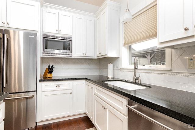 kitchen with white cabinets, tasteful backsplash, appliances with stainless steel finishes, and a sink