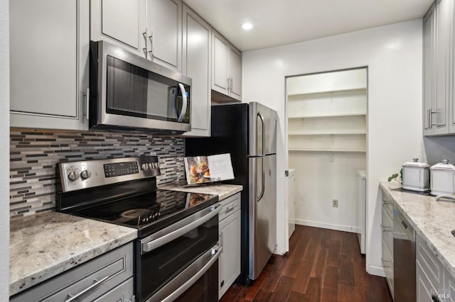 kitchen featuring light stone countertops, dark wood-style floors, appliances with stainless steel finishes, and backsplash