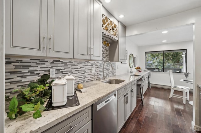 kitchen featuring light stone counters, dark wood-style floors, backsplash, stainless steel dishwasher, and a sink