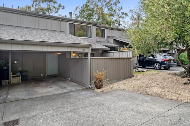 view of side of property with driveway and roof with shingles