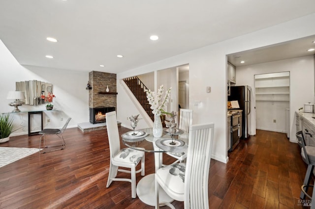 dining space featuring dark wood-style floors, recessed lighting, stairs, and a stone fireplace