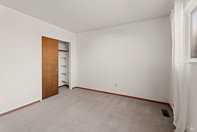 unfurnished bedroom with light carpet, a closet, visible vents, and baseboards