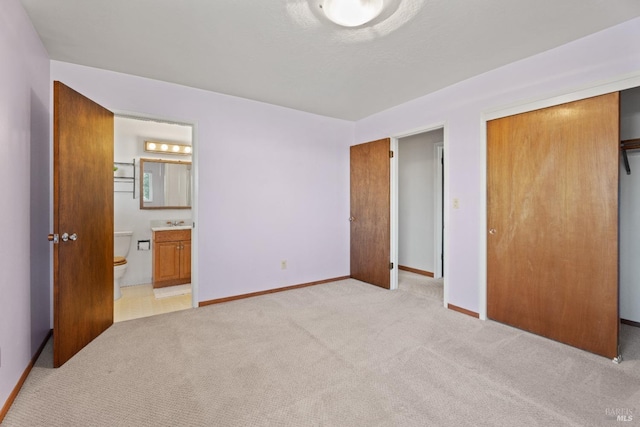 unfurnished bedroom featuring a closet, light colored carpet, connected bathroom, and baseboards