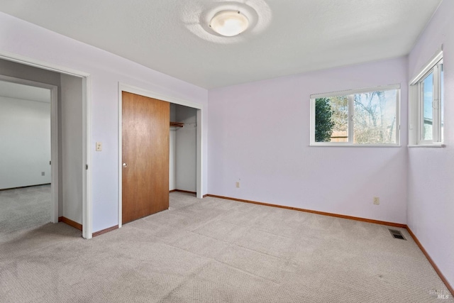 unfurnished bedroom featuring a closet, visible vents, light carpet, and baseboards