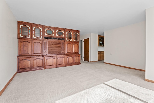 unfurnished living room featuring light colored carpet and baseboards