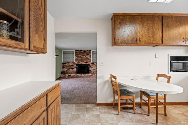 dining area featuring light carpet, a fireplace, and baseboards