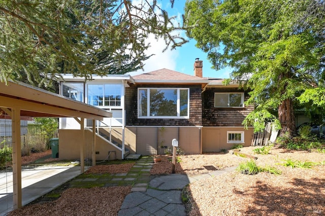 view of front of property featuring a carport, stairway, and a chimney