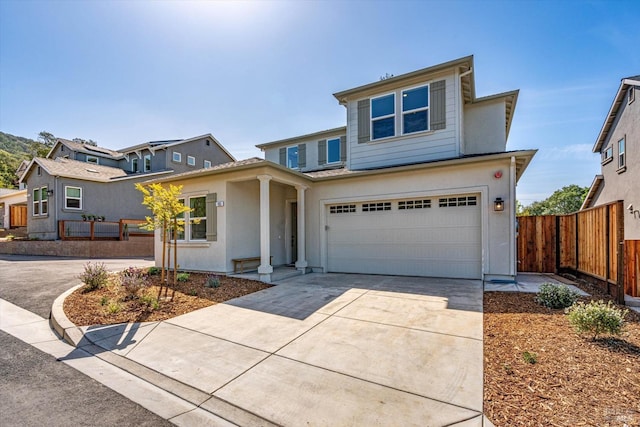 traditional home with concrete driveway, an attached garage, fence, and stucco siding