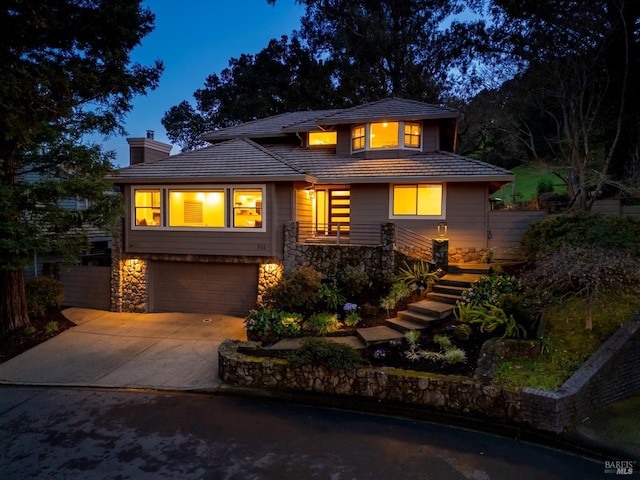 prairie-style house with a garage, concrete driveway, stone siding, a tile roof, and a chimney