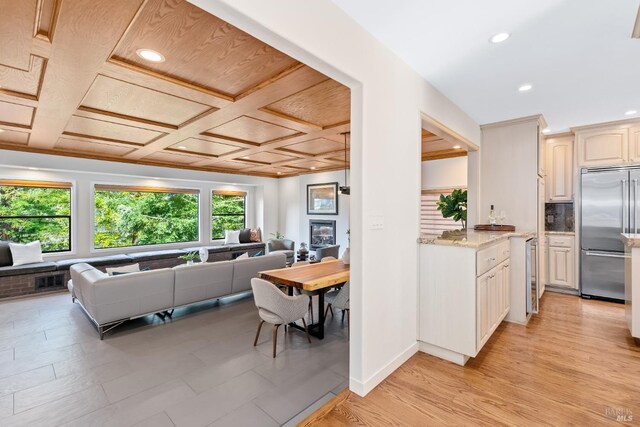 kitchen featuring baseboards, decorative backsplash, coffered ceiling, open floor plan, and stainless steel built in fridge