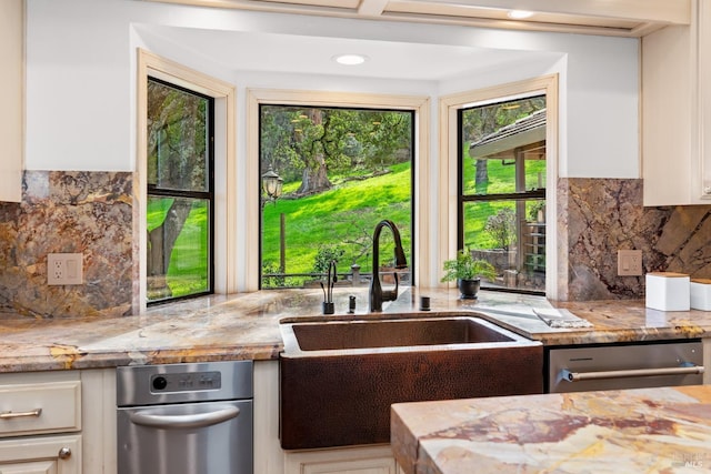 kitchen featuring light stone counters, decorative backsplash, white cabinetry, a sink, and dishwasher