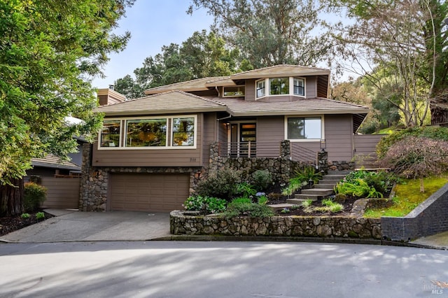 view of front of property with stone siding, an attached garage, a chimney, and concrete driveway