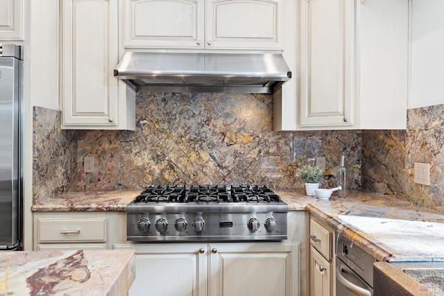 kitchen with light stone counters, stainless steel appliances, backsplash, and exhaust hood