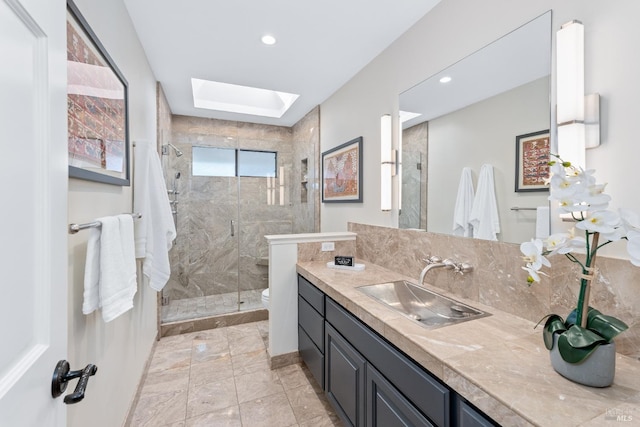 bathroom featuring a skylight, toilet, vanity, a shower stall, and recessed lighting