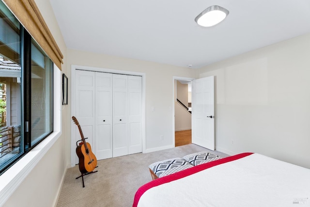 bedroom featuring baseboards, a closet, and light colored carpet