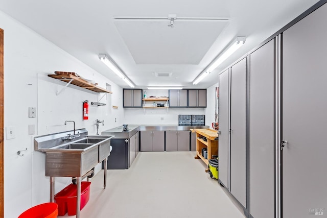 kitchen featuring finished concrete flooring, gray cabinets, and open shelves